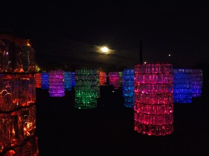 A beautiful art display involving plastic water bottles and light at the Desert Botanical Gardens in Phoenix, with the moon behind.